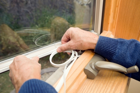 Putting weatherstripping on a window.