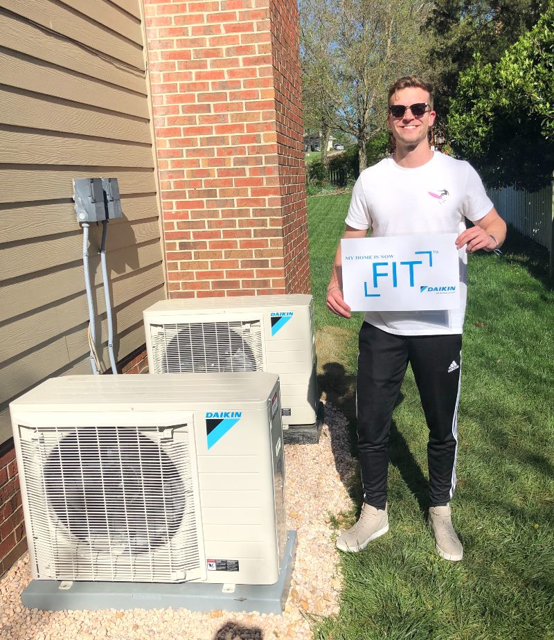 Customer holding Daikin Fit System poster next to hvac unit